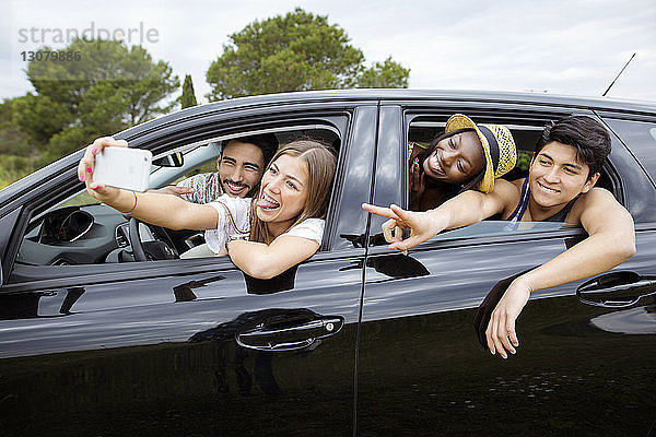 Fröhliche männliche und weibliche Freunde  die im Auto sitzen