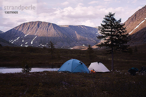 Zelte auf Campingplatz am See vor bewölktem Himmel