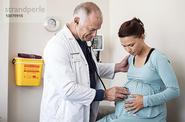 Arzt untersucht den Bauch einer Schwangeren im Untersuchungsraum