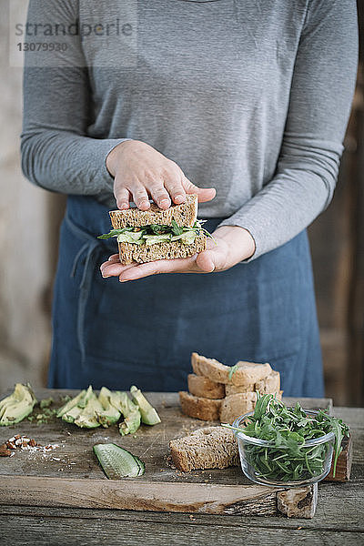 Mitschnitt einer Frau  die zu Hause auf einem Holztisch ein Sandwich macht