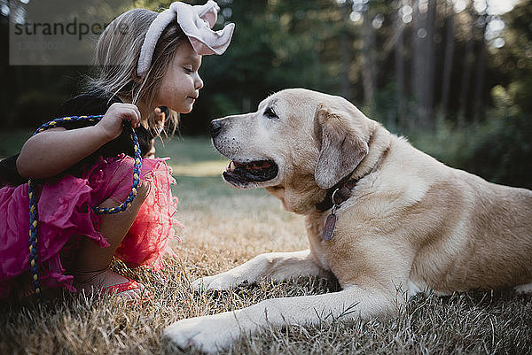 Seitenansicht eines Mädchens beim Spielen mit Hund auf dem Feld