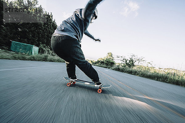 Rückansicht eines Mannes beim Skateboarden auf der Straße