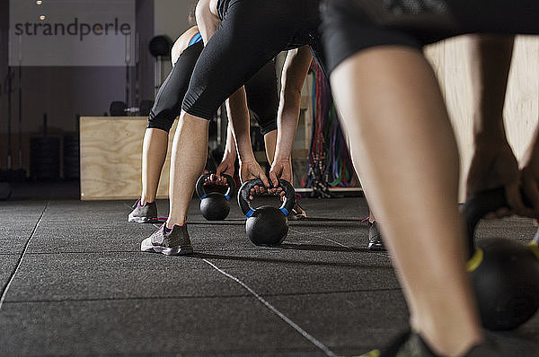 Untere Sektion von Sportlerinnen  die mit Kesselglocken im Fitnessstudio trainieren