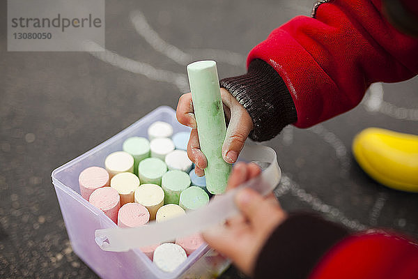 Ausgeschnittenes Bild eines Jungen  der mit Kreide auf der Straße spielt