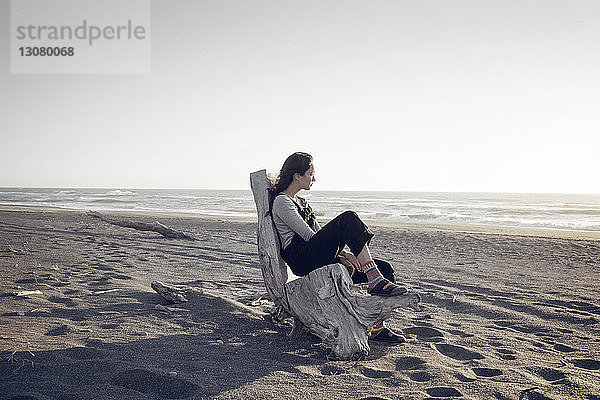 Nachdenkliche Frau entspannt sich am Strand im Wald