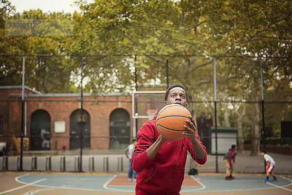 Student hält Basketball in der Hand und wirft einen Schlag  während er auf dem Platz spielt