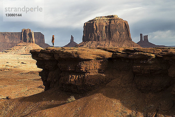 Mitteldistanzansicht einer Frau  die an einer Felsformation im Oljato-Monument Valley steht
