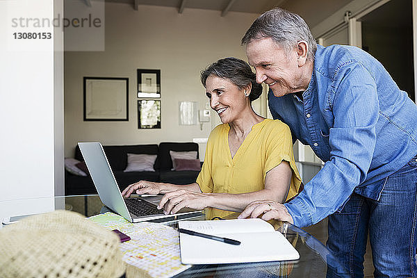 Älteres Ehepaar benutzt Laptop bei der Urlaubsplanung zu Hause