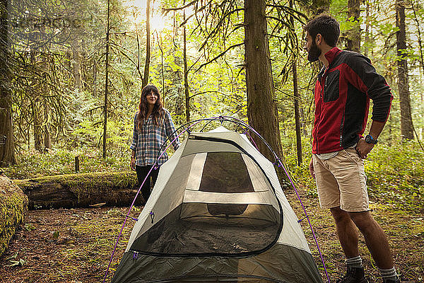 Paar sieht sich an  während es beim Zelt auf einem Feld im Wald steht