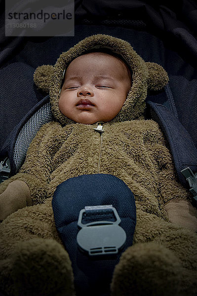 Hochwinkelansicht eines Kleinkindes im Bärenanzug  das im Auto schläft