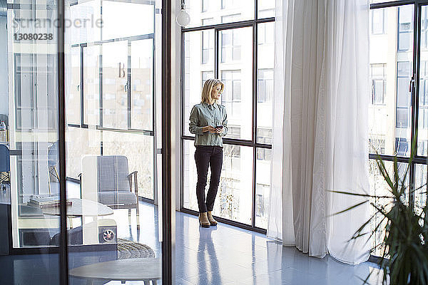 Geschäftsfrau  die im Amt stehend durch ein Fenster schaut