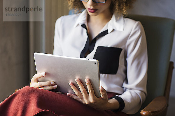 Mittelsektion einer Geschäftsfrau  die einen Tablet-Computer in der Hotellobby benutzt