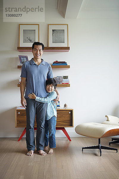 Porträt eines glücklichen Vaters und Sohnes  die zu Hause an der Wand stehen
