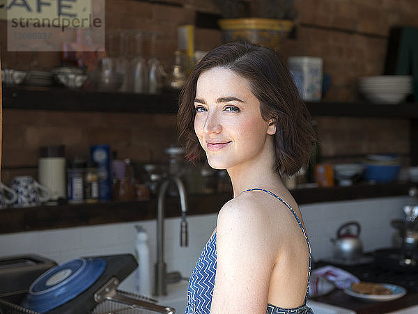 Porträt einer lächelnden jungen Frau  die in der Küche steht