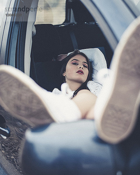 Porträt einer selbstbewussten Frau  die sich im Auto entspannt  durch Fenster gesehen