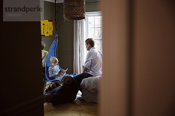 Vater sieht Sohn im Schlafzimmer beim Lesen an