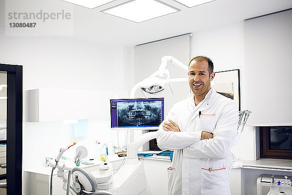 Porträt eines selbstbewussten Zahnarztes  der in der Klinik an der zahnärztlichen Ausrüstung steht