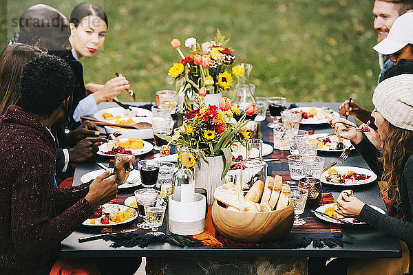 Freunde essen Essen  während sie im Garten am Esstisch sitzen