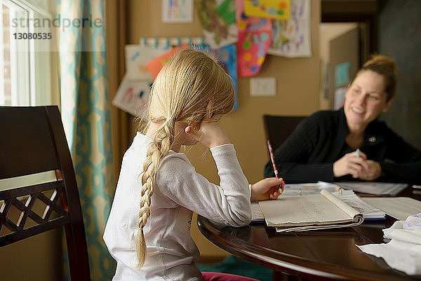 Mädchen lernt  während sie mit der Mutter zu Hause sitzt