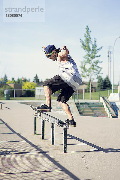 Junger Mann beim Skateboarden auf der Reling
