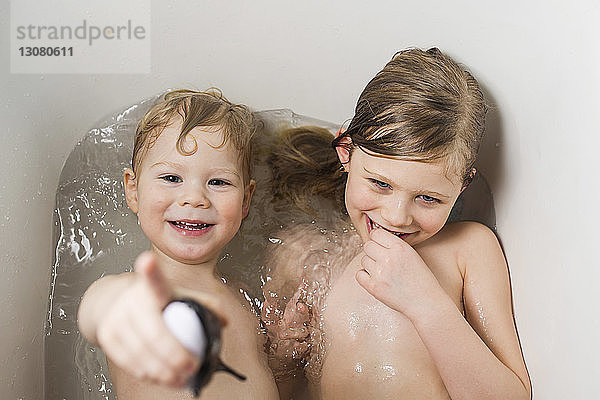 Porträt eines glücklichen Bruders mit einer Schwester  die zu Hause in der Badewanne badet