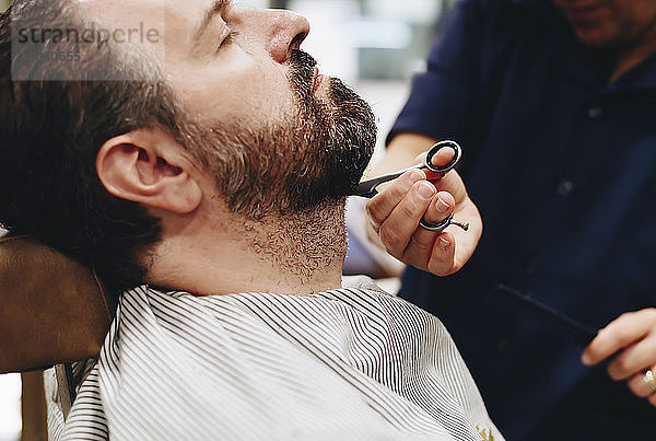 Mittelteil eines Barbiers  der im Salon einen Bart schneidet