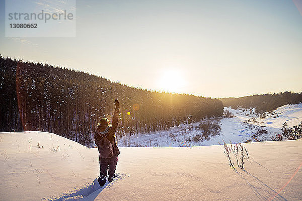 Rückansicht einer Frau  die auf einem schneebedeckten Feld gegen den Himmel gestikuliert