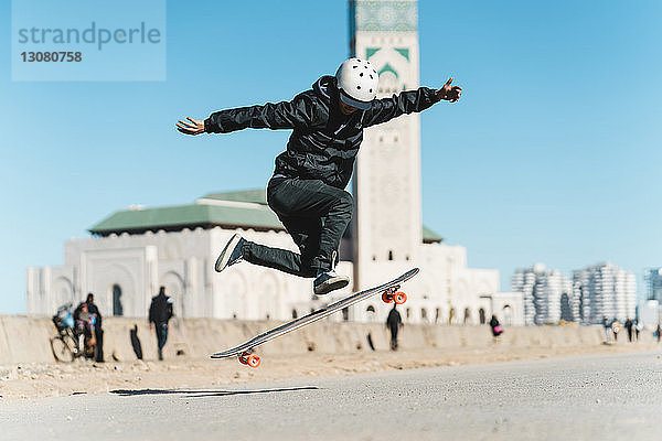 Mann führt Stunt beim Skateboardfahren gegen die Moschee Hassan II aus
