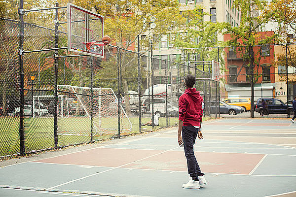 Schüler in voller Länge spielt auf dem Basketballplatz der Stadt