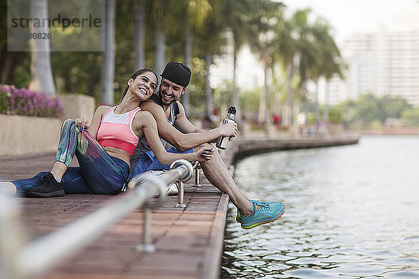 Glückliches Paar sitzt und genießt auf einem Holzsteg am Flussufer