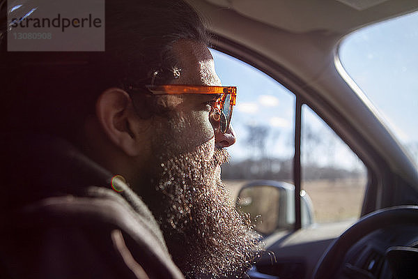 Nahaufnahme der Seitenansicht eines nachdenklichen männlichen Hipsters  der im Auto sitzt