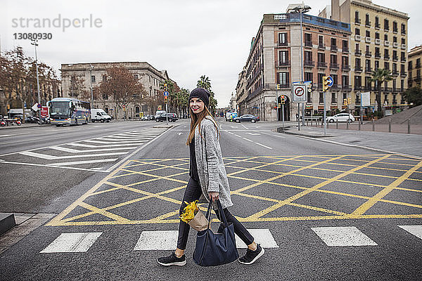 Porträt einer Frau  die einen Blumenstrauss in einer Tasche trägt  während sie auf der Strasse der Stadt geht