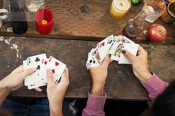 Draufsicht auf Freunde  die Karten spielen  während sie am Picknicktisch sitzen