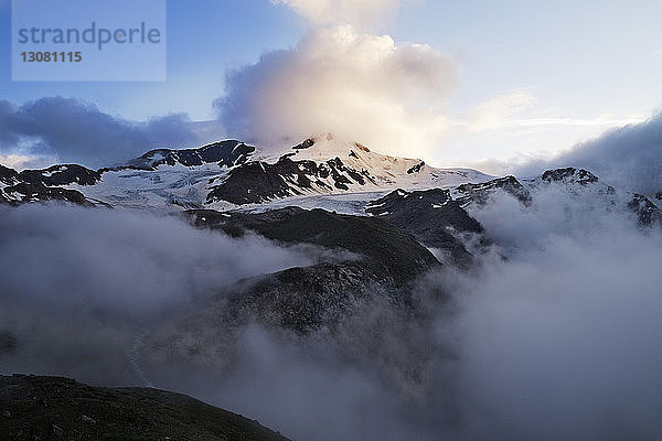 Szenische Ansicht eines schneebedeckten Berges mit Wolken