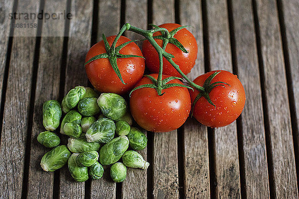 Draufsicht auf frische Tomaten und kleine Kohlköpfe auf Holztisch