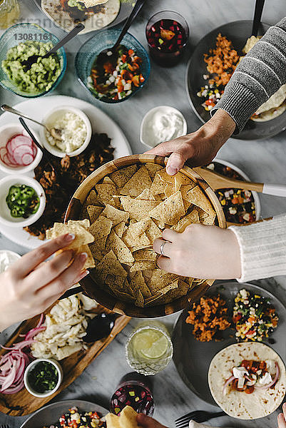 Draufsicht auf Freunde  die während des geselligen Beisammenseins Nacho-Chips bei Tisch essen