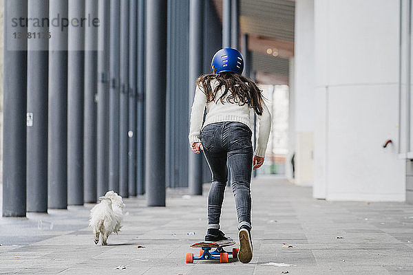 Rückansicht einer Frau beim Skateboarden auf dem Gehsteig