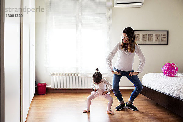 Lächelnde Mutter imitiert Mädchen beim Ballett-Tanz im Schlafzimmer