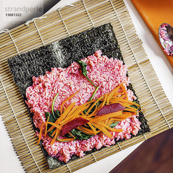 Draufsicht auf Gemüse und Sushi-Reis auf Nori bei Tisch