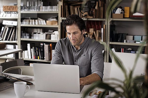 Männlicher Innenarchitekt mit Laptop am Schreibtisch im Büro