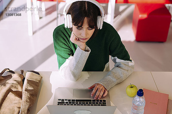 Hochwinkelansicht einer Frau  die einen Laptop benutzt  während sie in der Bibliothek sitzt
