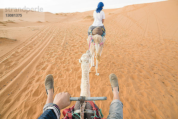 Freunde reiten auf Kamelen in der Wüste von Merzouga