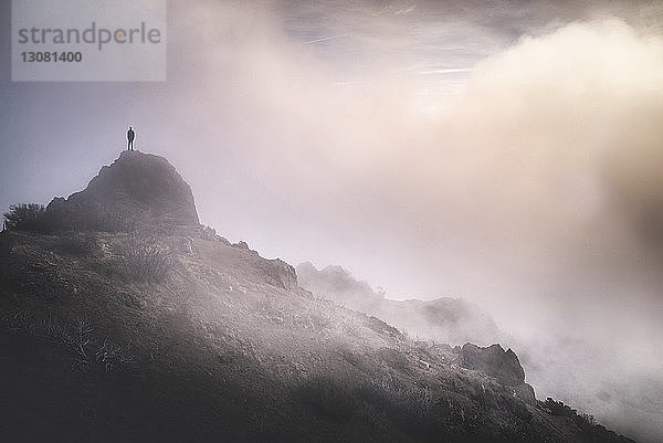Einsamer Mann steht bei Nebel auf Berg