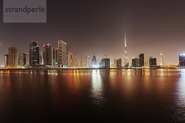 Beleuchtetes Stadtbild und Dubai Creek gegen klaren Himmel in der Dämmerung