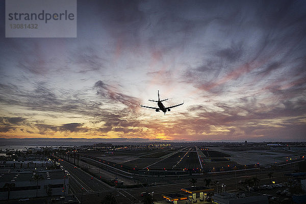 Silhouettenflugzeug landet auf Flughafen