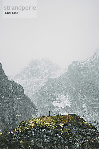 Fernsicht einer Person  die im Winter auf einem Berg steht