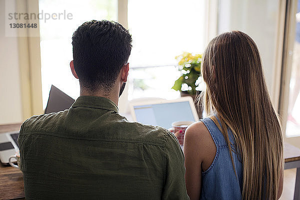 Rückansicht des Paares mit Laptop zu Hause