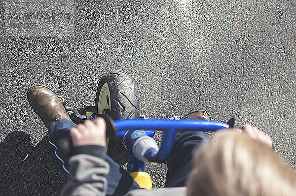 Hochwinkelaufnahme eines Jungen  der auf der Straße Fahrrad fährt