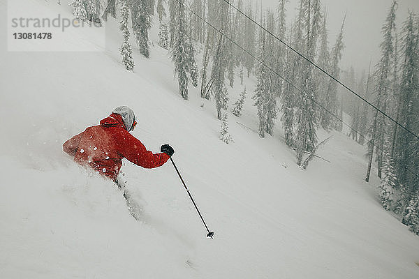 Hochwinkelaufnahme eines Mannes beim Skifahren auf einem schneebedeckten Berg