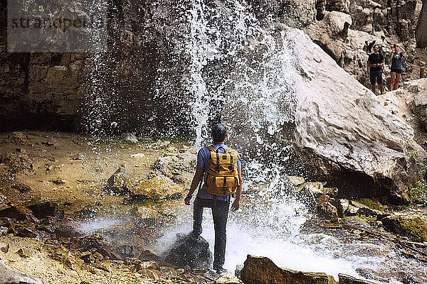 Rückansicht eines Mannes  der unter einem Wasserfall am Hängenden See steht
